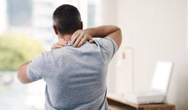 A man holds his neck in pain due to a neck and back injury sustained in a truck accident.