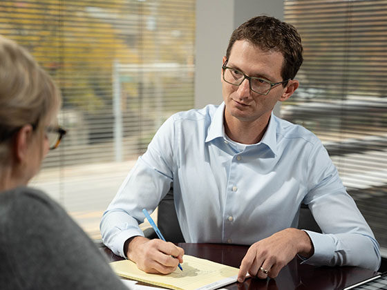 concerned male defective product attorney taking notes with client