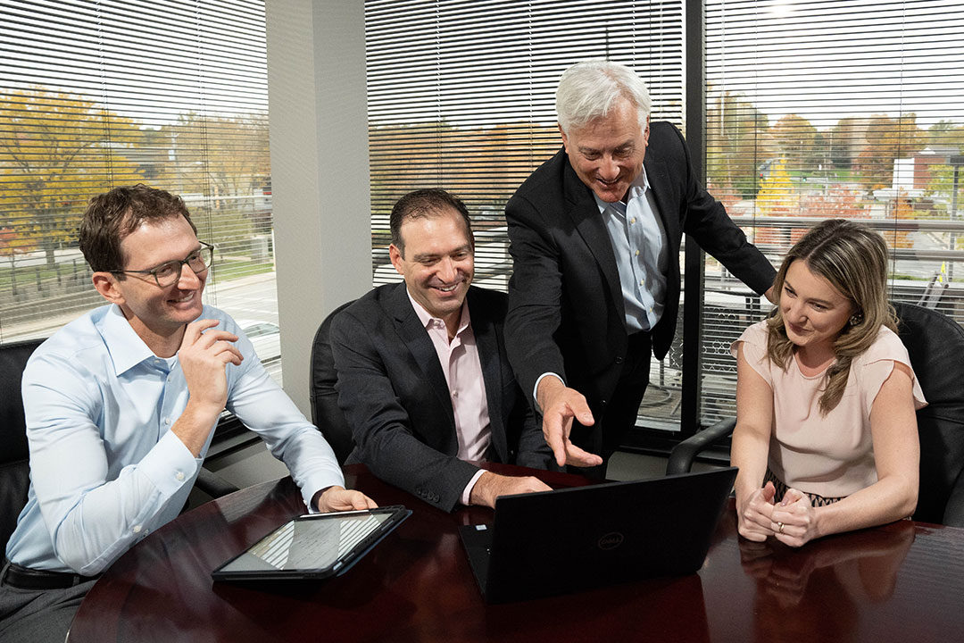 four personal injury attorneys looking at computer smiling