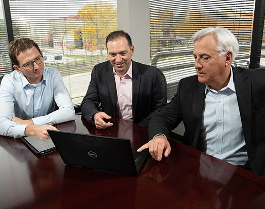 three personal injury attorneys in meeting pointing to computer