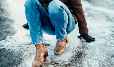 A woman in jeans and boots experiencing a slip and fall on icy sidewalks