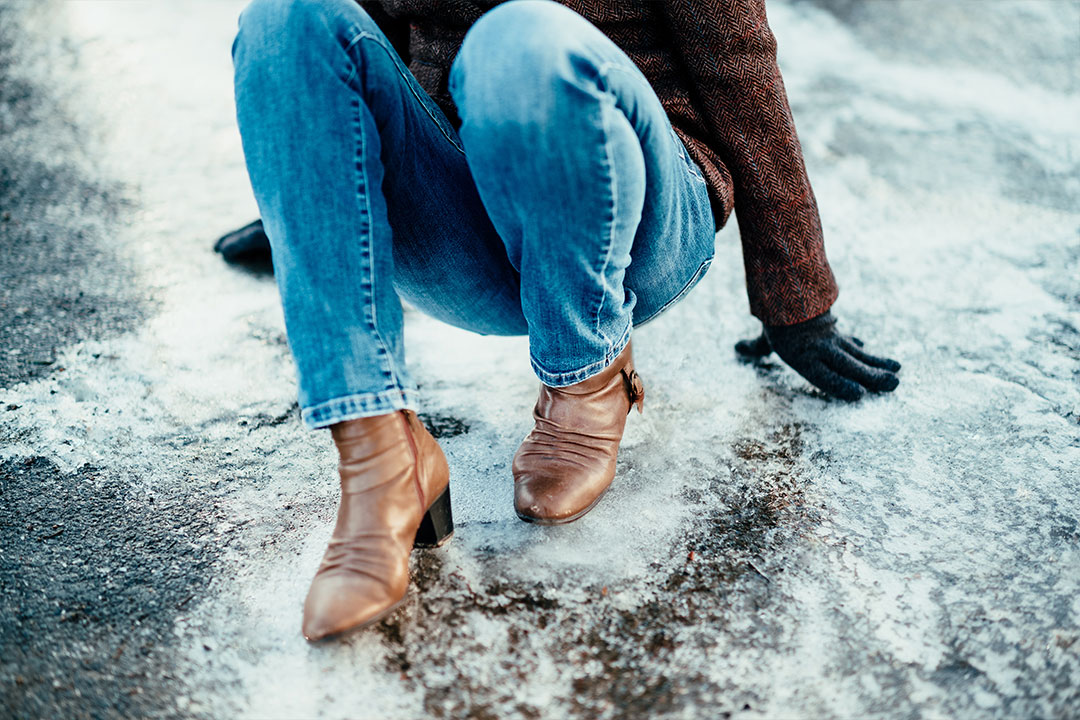 A woman in jeans and boots experiencing a slip and fall on icy sidewalks
