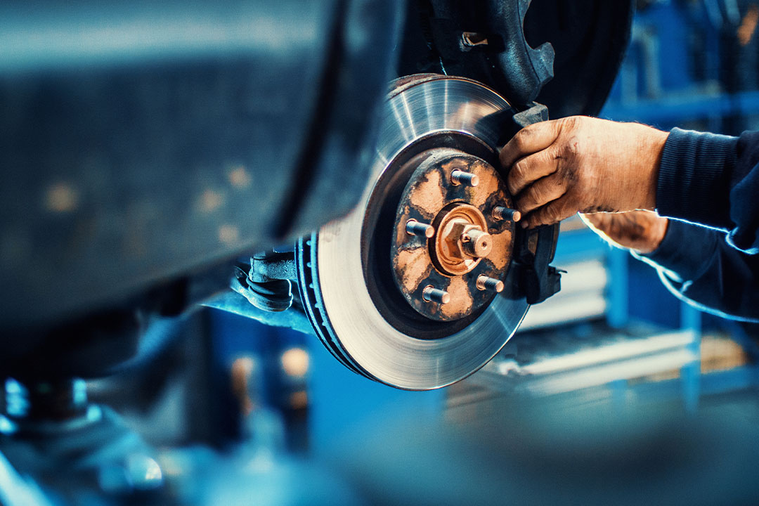 A man changes a defective car brake, which led to an injury case requiring a defective product attorney.