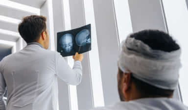 A man with a catastrophic injury to his head sits while the doctor views his x-rays.