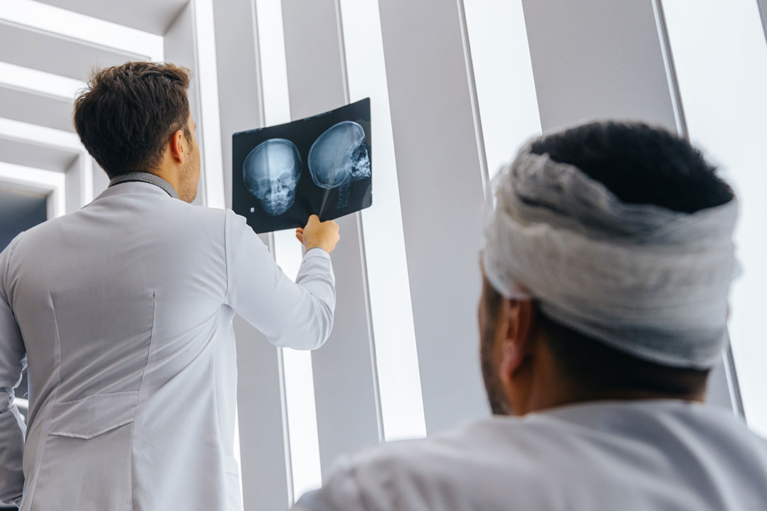 A man with a catastrophic injury to his head sits while the doctor views his x-rays.