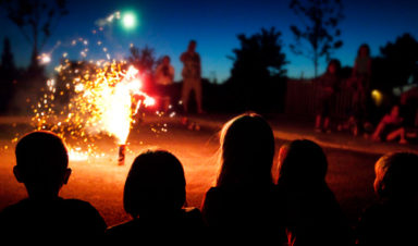 A group of people avoid fireworks injuries by celebrating safely from a distance late at night.