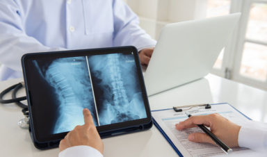 Two spinal cord injury attorneys meet at a desk to review scans of a catastrophic injury on a tablet.