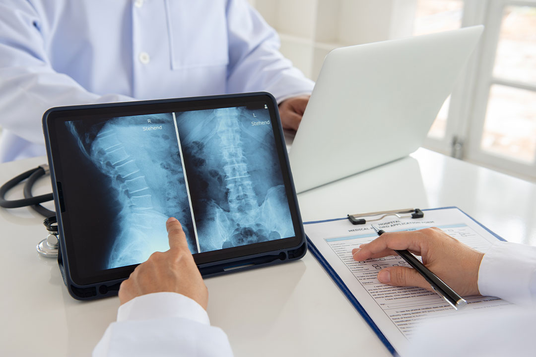 Two spinal cord injury attorneys meet at a desk to review scans of a catastrophic injury on a tablet.