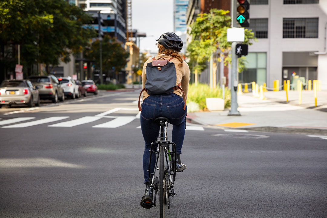 A woman bikes on a busy street wearing a helmet to avoid a dangerous bike accident.