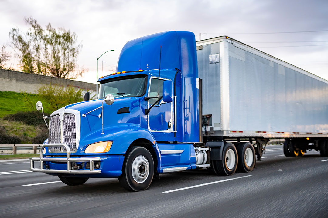 blue semi truck driving on the highway prior to an accident that required truck injury lawyers