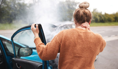 women looking at crashed car wondering if she can file a whiplash injury claims