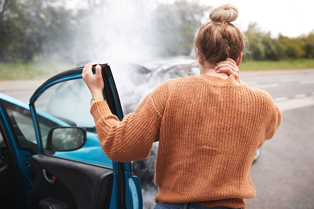 women looking at crashed car wondering if she can file a whiplash injury claims