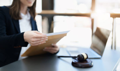 A St. Louis personal injury lawyer holds some paperwork at a desk, with a gavel and a laptop sitting on the desktop.