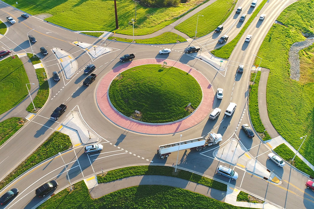 Birds-eye view of multiple cars entering a four-way roundabout