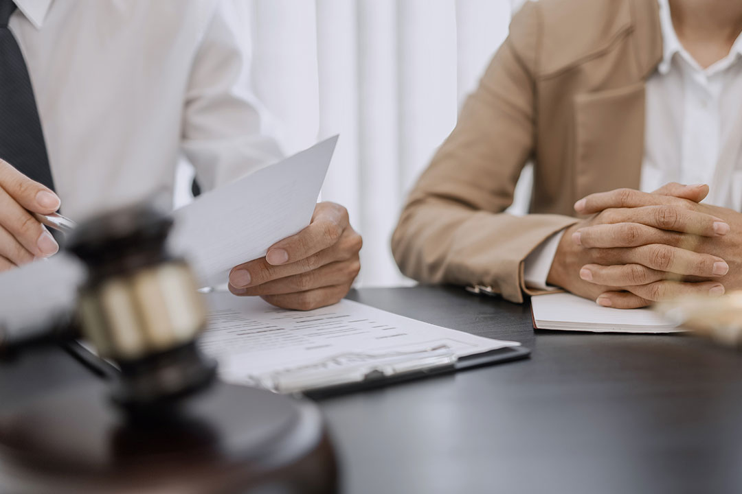 An attorney and their client go over paperwork at a wooden table in a discussion which will be protected under attorney-client privilege